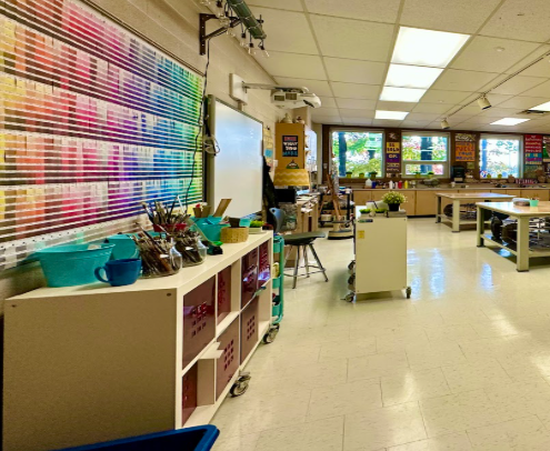 Large classroom, with colour palettes on wall above a cabinet of art supplies