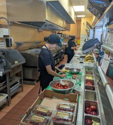 Co-op student working in a kitchen cutting fruit.